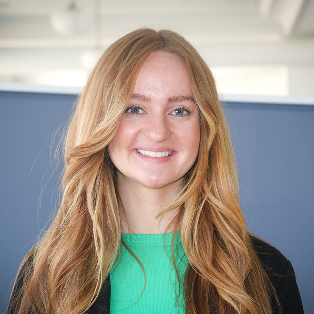 Headshot of redheaded female in green shirt and black blazer.